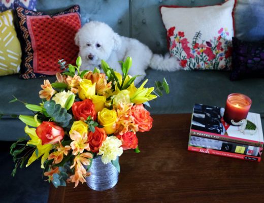 Bouquet of flowers in a vase with a dog on a couch nearby.