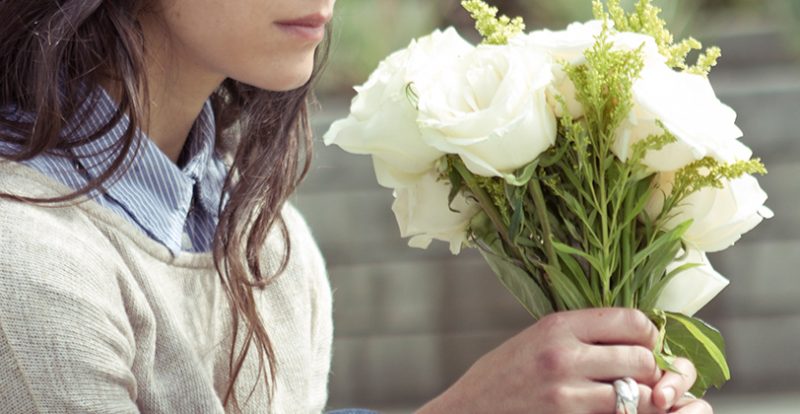 long-haired person holding a bouquet of white flowers