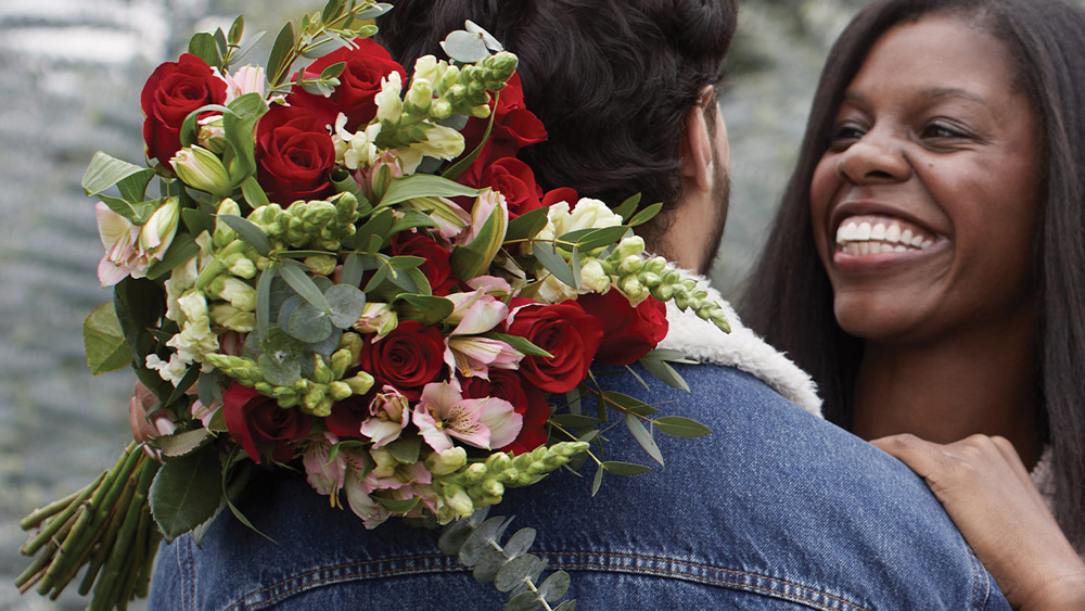 man and women holding flowers for valentines day