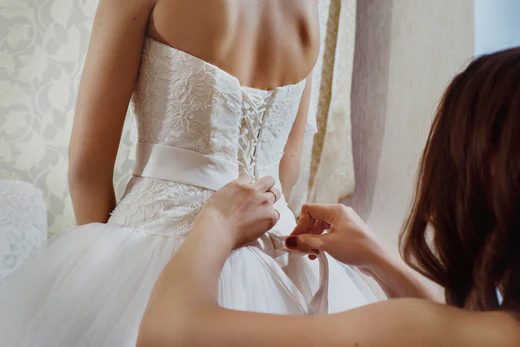 maid of honor helping bride with her dress