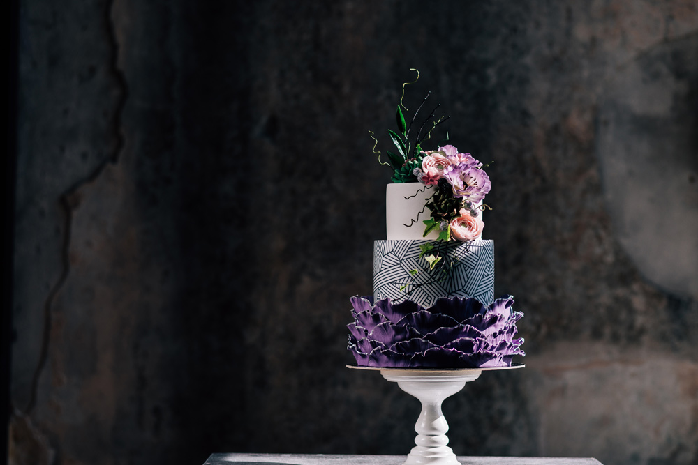 wedding cake in purples and dark tones with flowers decorating it