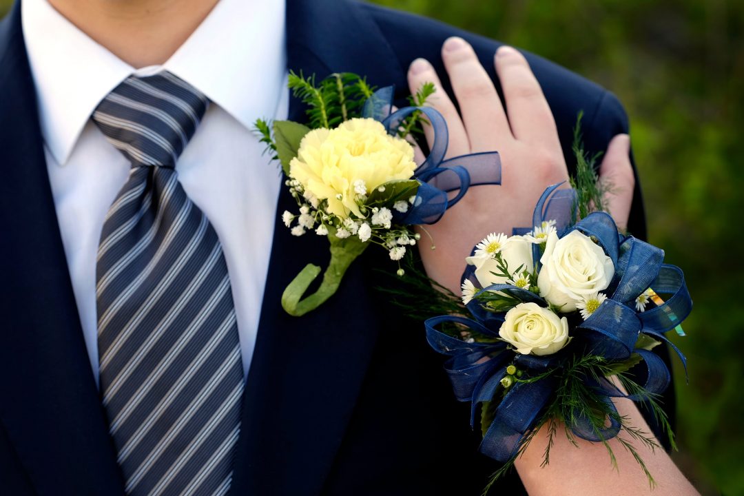 Woman's hand on prom date's shoulder, showing corsage and boutonniere
