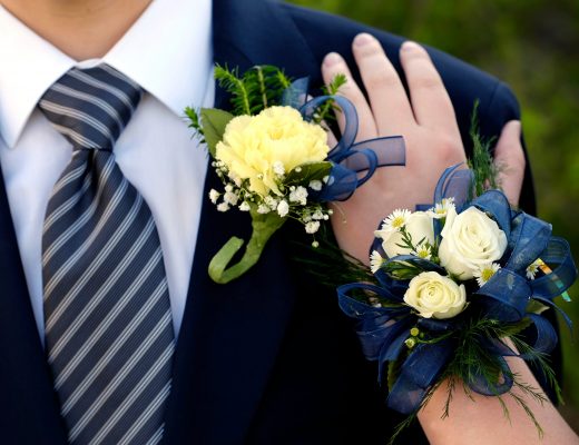 Woman's hand on prom date's shoulder, showing corsage and boutonniere