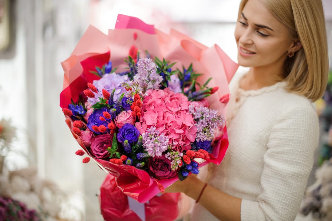 Young woman holding a bouquet of flowers, including hydrangeas