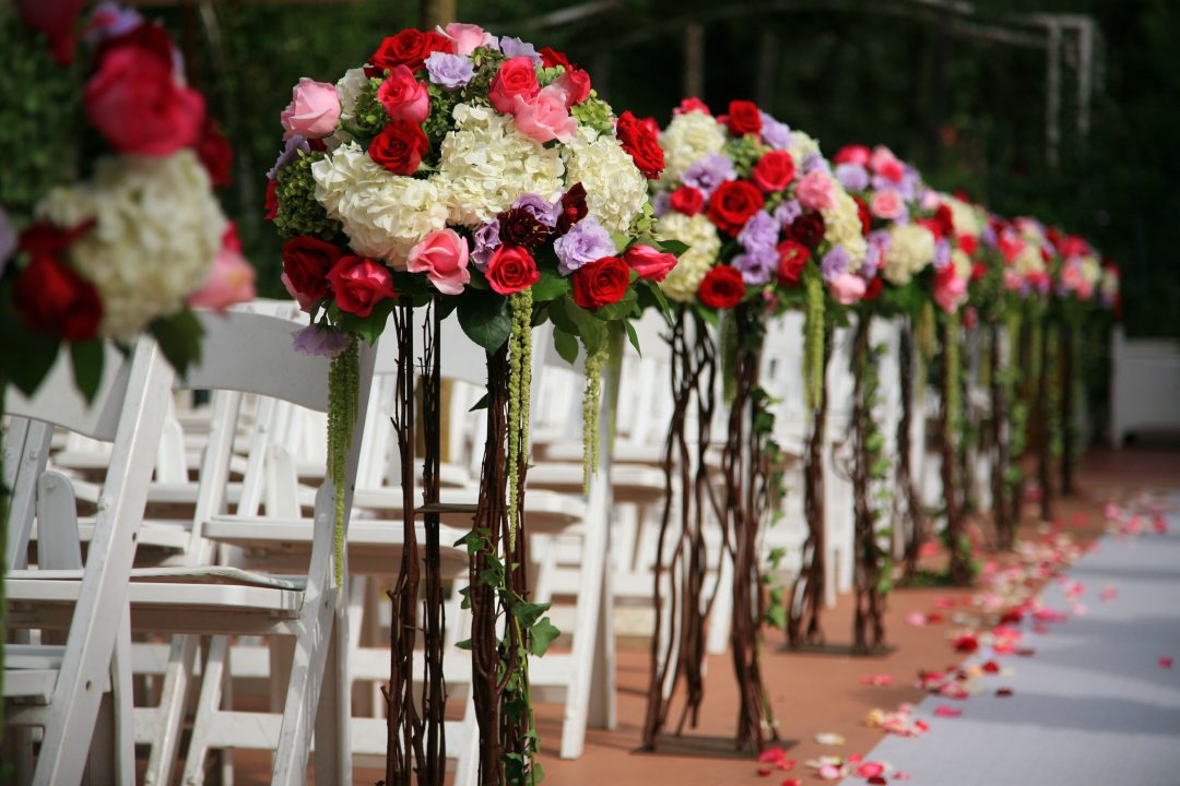 Wedding aisle decorated with flower arrangements on the end of chairs