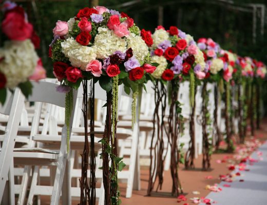 Wedding aisle decorated with flower arrangements on the end of chairs