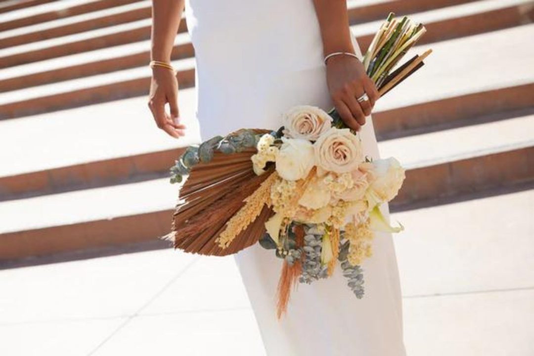 Bride holding bouquet of dried flowers at her side