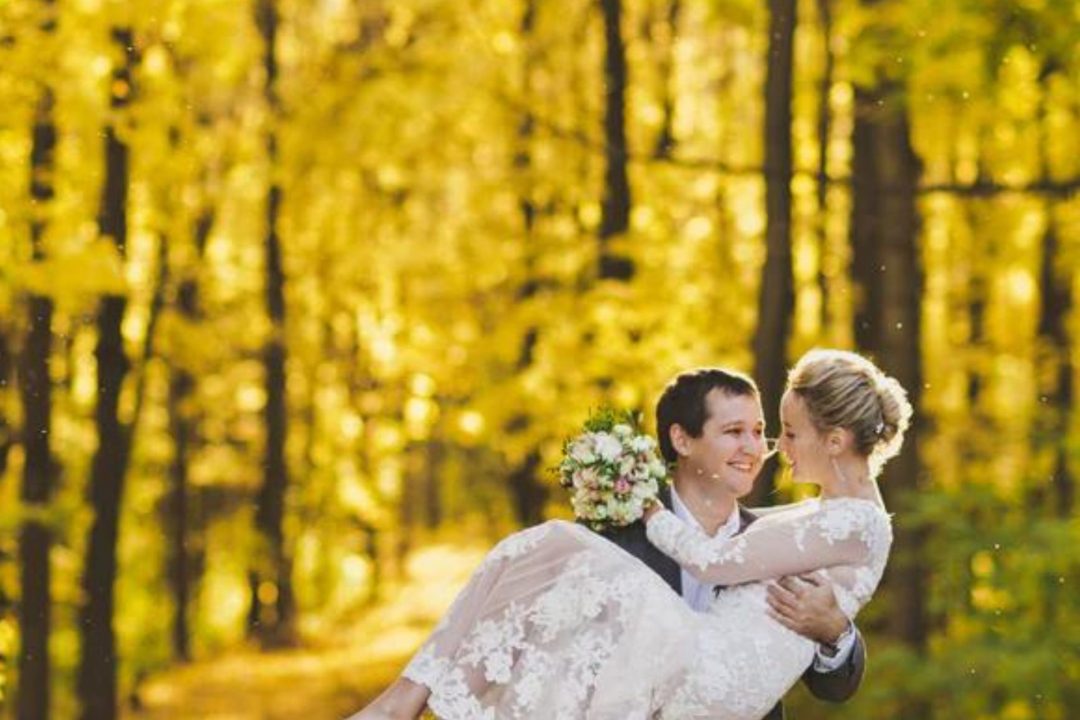 Groom holds his bride in a golden-lit forest