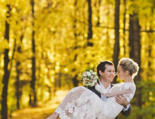 Groom holds his bride in a golden-lit forest