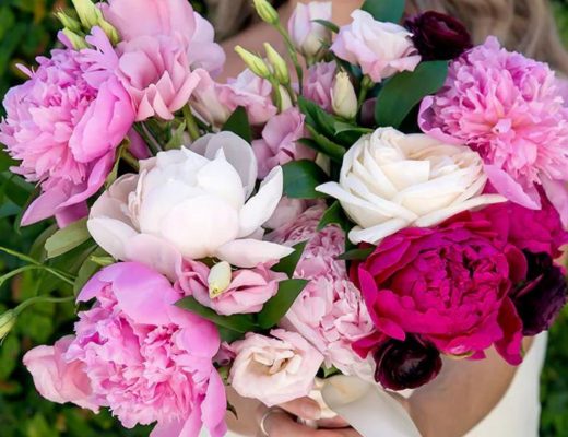 Close-up of bride holding a bouquet of white and pink peonies