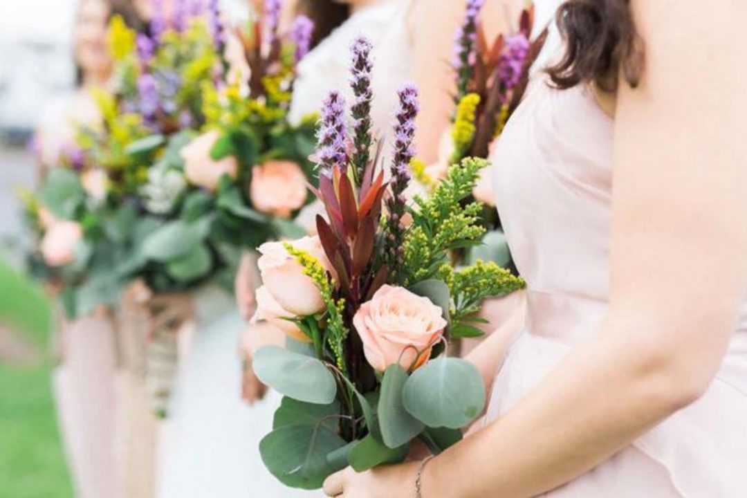 Lineup of bridesmaids holding spring flower wedding bouquets