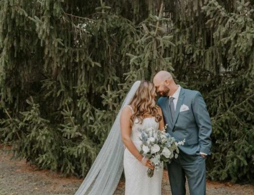 Bride and groom embracing in front of pine trees