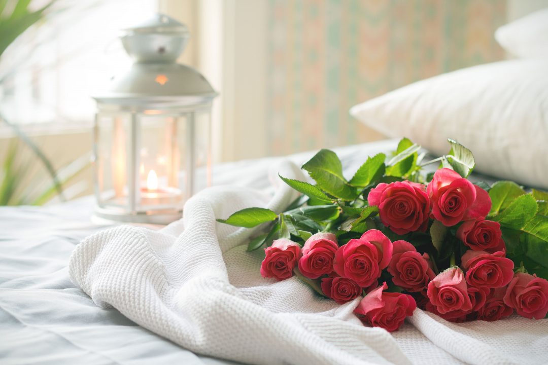 Pink-red roses laid out on a bed