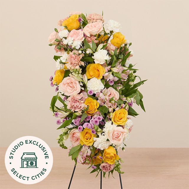 mixed floral casket spray in yellow, white, pink and other pastel colors